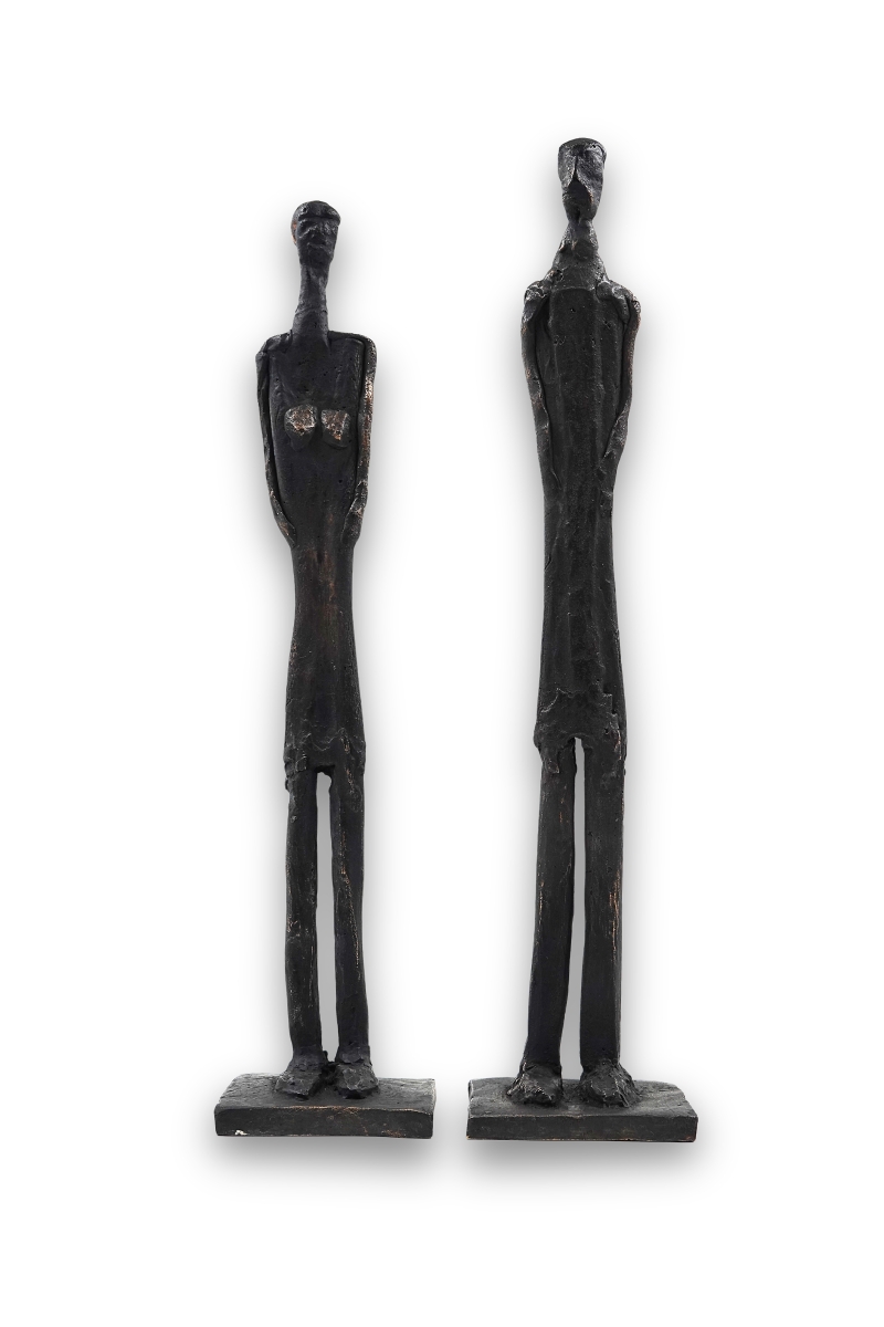 Zwei schlanke Bronzefiguren mit archaischer Formensprache auf integrierten Sockeln, schwarz patiniert.